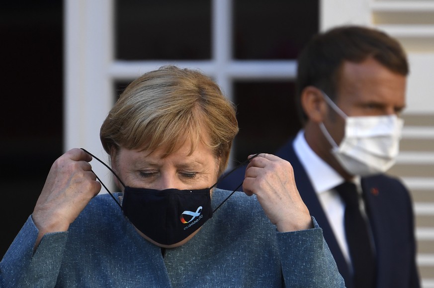 epa08614968 German Chancellor Angela Merkel wears a face mask as she arrives with French president Emmanuel Macron for a press conference after a meeting at Fort de Bregancon, in Bormes-les-Mimosas, s ...
