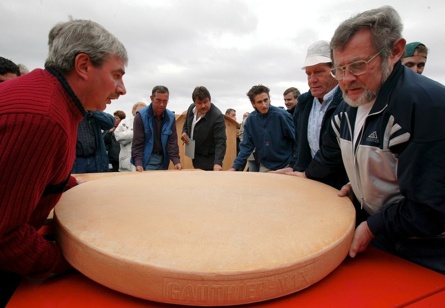 Des personnes prepare la coupe du fromage, photographies ce dimanche 26 septembre 2004 a l&#039;alpage de Nax, quelque 300 personnes sont venues deguster la raclette faite avec le plus gros fromage a  ...