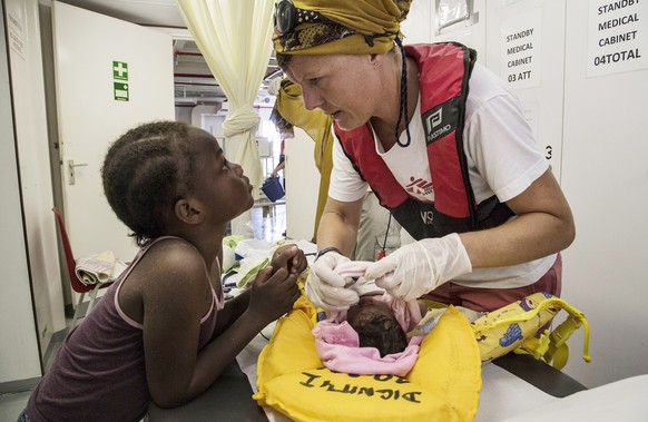 In this photo provided by Doctors Without Borders and taken on Sunday, July 19, 2015, Barbora Sollerova, a midwife with the organization, tends to a newborn baby who was rescued with other migrants in ...