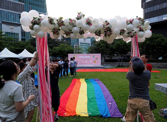 epa07594614 LGBT activists erect an archway for gay couples to wall the red carpet - made with a rainbow flag - to a stage near the Taipei 101 skyscraper in Taipei, Taiwan, 23 May 2019. On 24 May, Tai ...