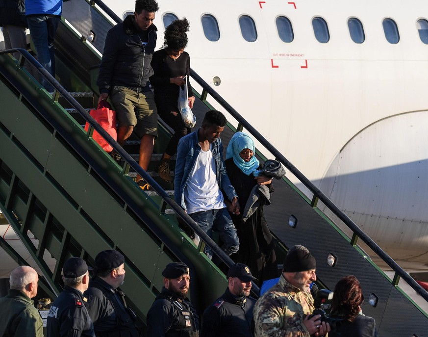 epa07536717 Asylum seekers disembark from a plane as 147 asylum seekers from Misurata (Libya) arrive at the Pratica di Mare military airport, near Rome, Italy, 29 April 2019, following the opening of  ...