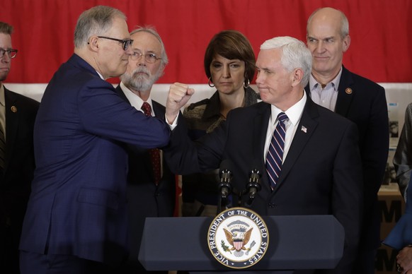 Vice President Mike Pence bumps elbows with Washington Gov. Jay Inslee, left, during a news conference, Thursday, March 5, 2020 at Camp Murray in Washington state. Pence was in Washington to discuss t ...