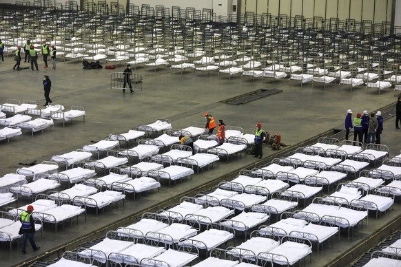Workers arrange beds in a convention center that has been converted into a temporary hospital in Wuhan in central China&#039;s Hubei Province, Tuesday, Feb. 4, 2020. China said Tuesday the number of i ...