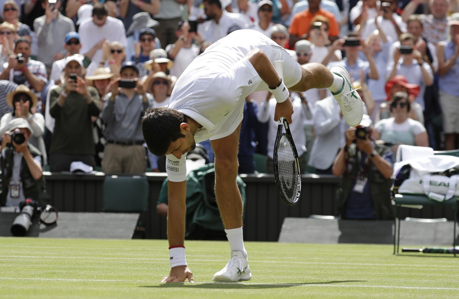 Serbia&#039;s Novak Djokovic celebrates by touching the court after beating Germany&#039;s Philip Kohlschreiber in a Men&#039;s singles match during day one of the Wimbledon Tennis Championships in Lo ...