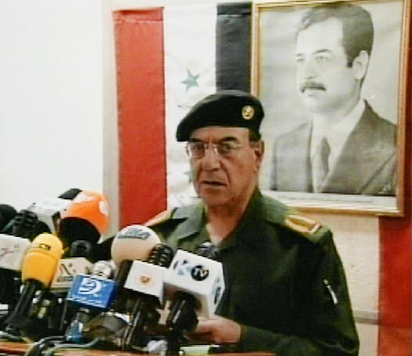Iraqi Information Minister Muhammad Said al-Sahhaf, stands in front of a photo of Iraqi President Saddam Hussein in this image from video, as he speaks during a news conference in Baghdad, Saturday, M ...