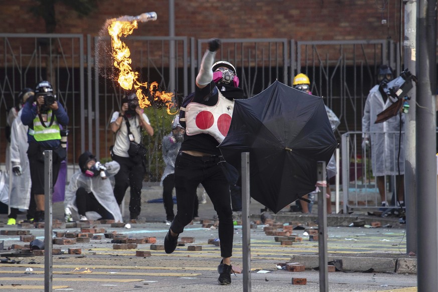 A protestor throws a molotov cocktail during a confrontation with police at Hong Kong Polytechnic University in Hong Kong, Sunday, Nov. 17, 2019. A Hong Kong police officer was hit in the leg by an ar ...