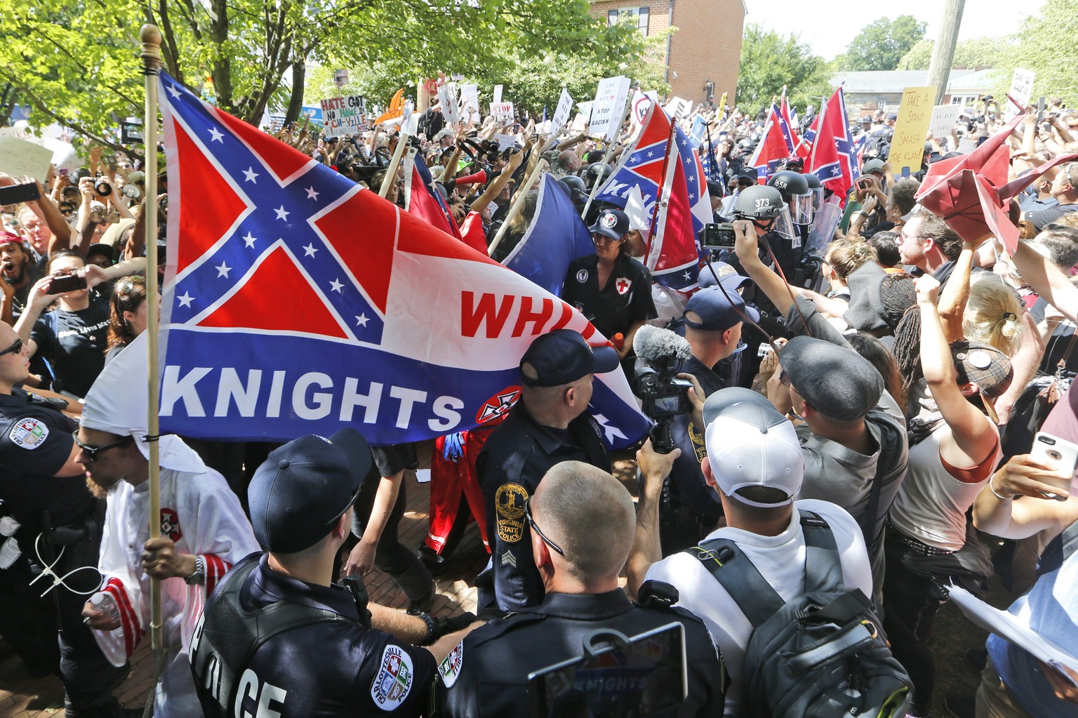 This July 8, 2017 photo shows members of the KKK escorted by police past a large group of protesters during a KKK rally in Charlottesville, Va. Some white Southerners are again advocating for what the ...