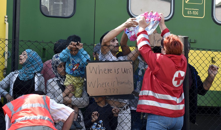 Helfer des Roten Kreuzes geben Flüchtlingen Wasser.