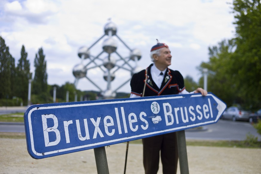 Dressed in a traditional Swiss costume, &quot;Mister Swiss&quot; passes on his way to the city of Brussels, June 8, 2011, the &quot;Atomium&quot; which was erected in 1958 for the World Exhibition in  ...