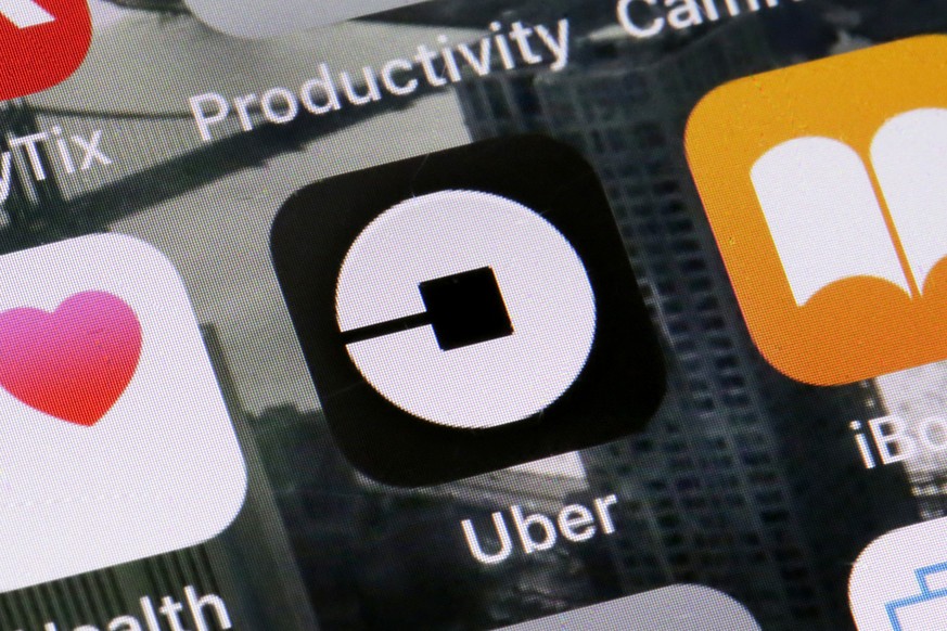 FILE - This Tuesday, June 12, 2018, file photo shows the Uber app on a phone in New York. On Monday, July 9, 2018, Uber said it is getting into the scooter-rental business, and is investing in Lime, a ...