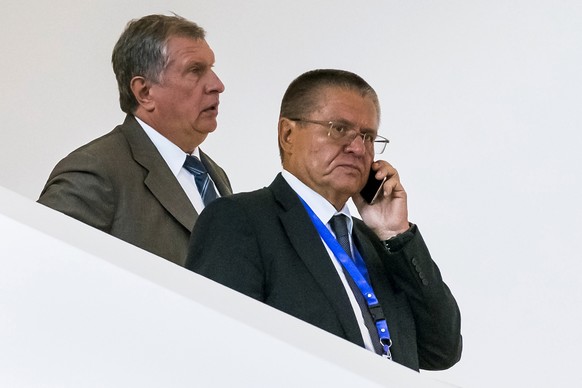 In this Monday, Aug. 8, 2016 photo, Economic Development Minister Alexei Ulyukayev, right, speaks on a mobile phone as he attends a meeting with Rosneft CEO Igor Sechin, left, in Baku, Azerbaijan. Rus ...