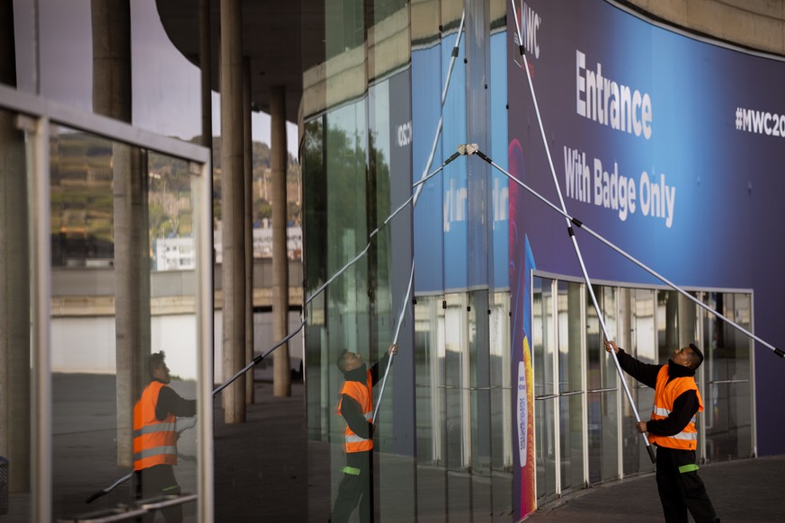 Workers clean the windows in one of the entrances at the Mobile World Congress 2020 venue in Barcelona, Spain, Tuesday, Feb. 11, 2020. Intel Mobile is the latest company announcing that is pulling out ...