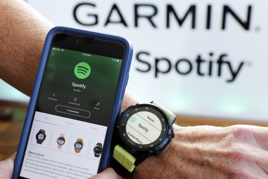 FILE- In this Oct. 3, 2018, file photo a Garmin International employee shows the new Spotify app on his smartphone integrated with his Garmin fenix 5 Plus watch during a presentation in New York. Spot ...