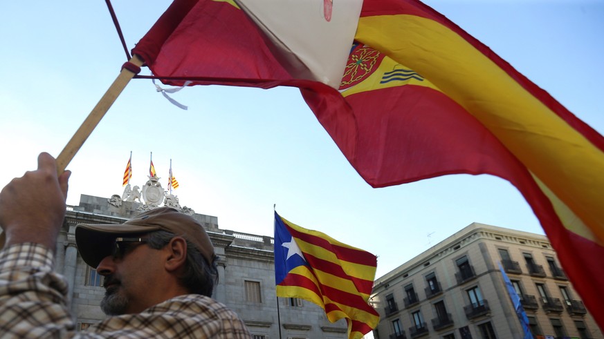 epa06297812 A demonstrator waves Spanish national flag in front of a Catalonian pro-independence one (C) outside Palau de la Generalitat (rear), the Catalonian regional Government Palace, in the first ...