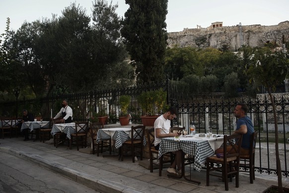 epa08789029 Tourist sit at a table at a restaurant at the tourist district of Plaka in central Athens, Greece, 31 October 2020. Greece will shut down, for the first time since May, restaurants, bars,  ...