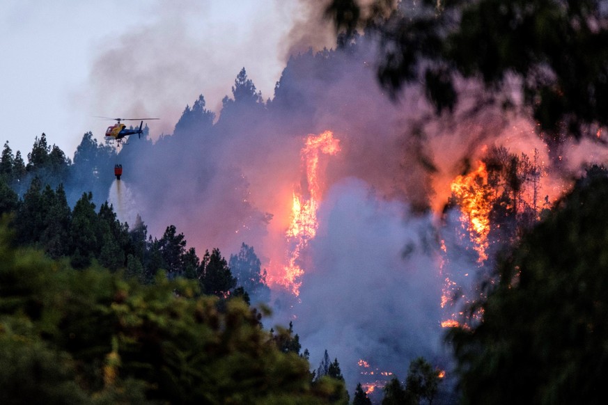 epa07778561 A firefighting helicopter spreads water over a forest fire broke up in the village of Valleseco, Gran Canaria island, Spain, 17 August 2019. Three roads had to be closed due to the fire. T ...