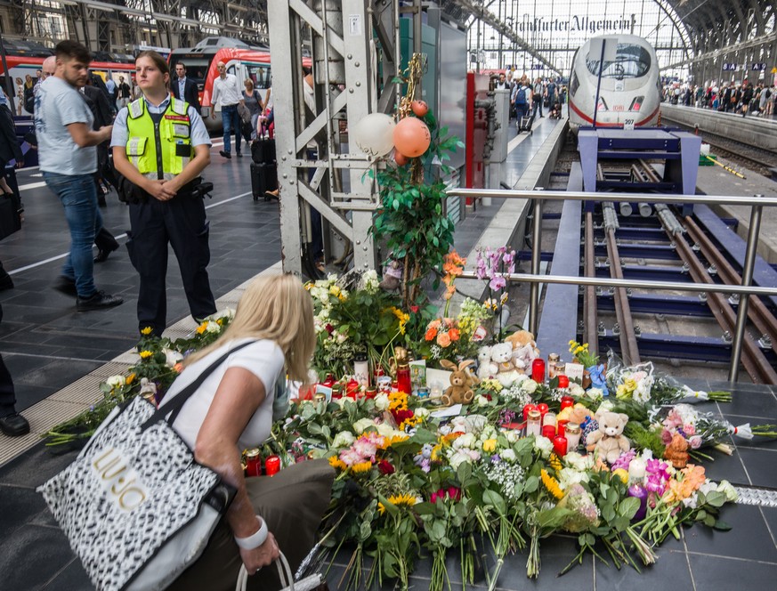 30.07.2019, Hessen, Frankfurt/Main: Eine Frau legt am Bahnsteig 7 im Frankfurter Hauptbahnhof Blumen nieder. Ein achtjähriger Junge ist im Frankfurter Hauptbahnhof von einem Mann vor den einfahrenden  ...