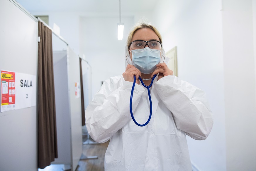 epa08389917 A doctor wearing a protective face mask waits for patients at the coronavirus test centre in Mendrisio, Switzerland, 28 April 2020. The test centre is one of four test centres in Ticino, w ...