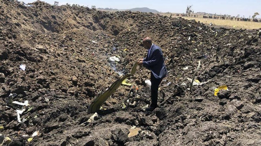 In this photo taken from the Ethiopian Airlines Facebook page, the CEO of Ethiopian Airlines, Tewolde Gebremariam, looks at the wreckage of the plane that crashed shortly after takeoff from Addis Abab ...