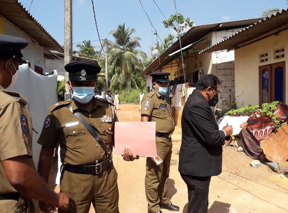 Sri Lankan magistrate Wasantha Ramanayake, right and police officers inspect outside a house where a nine year old girl was canned to death in Delgoda, Sri Lanka, Sunday, Feb.28, 2021. Police in Sri L ...