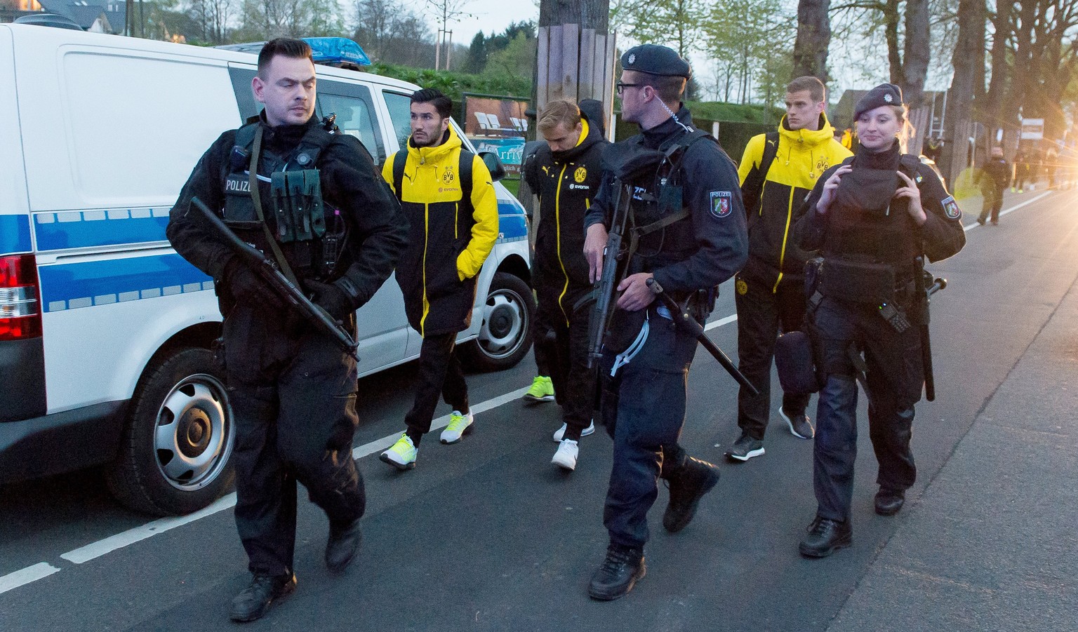 epa05903388 Borussia Dortmund players (L-R) Nuri Sahin, Marcel Schmelzer and Sven Bender are escorted by police after their team bus was hit by three explosions ahead of their UEFA Champions League so ...