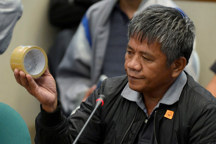 Edgar Matobato, a self-confessed former hitman, holds up a roll of tape, the type of which he claims he used on his victims, during a senate hearing on drug-related extra-judicial killings, in Pasay c ...