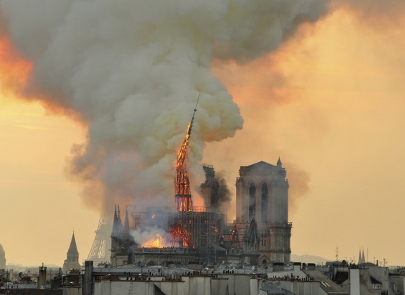 In this image made available on Tuesday April 16, 2019 flames and smoke rise from the blaze as the spire starts to topple on Notre Dame cathedral in Paris, Monday, April 15, 2019. An inferno that rage ...