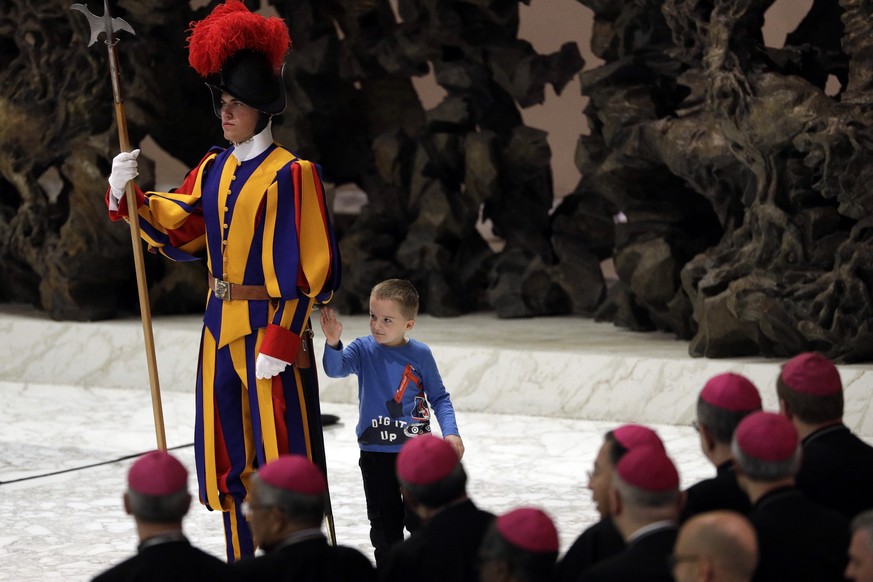 A child plays with a Swiss guard in the Paul VI Hall at the Vatican, Wednesday, Nov. 28, 2018. Pope Francis has praised the freedom, albeit undisciplined, of a hearing impaired child who climbed onto  ...