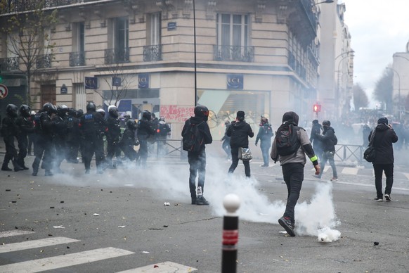 epa08864959 Protesters avoid tear gas during clashes with French riot Police during a protest against France&#039;s controversial global security law, during a protest in a street between Porte des Li ...
