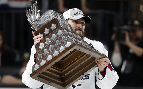Washington Capitals left wing Alex Ovechkin, right, of Russia, holds the Conn Smythe Trophy after the Capitals defeated the Golden Knights 4-3 in Game 5 of the NHL hockey Stanley Cup Finals Thursday,  ...