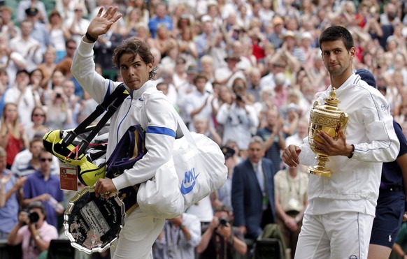 epa02808667 Novak Djokovic of Serbia (R) holds the championship trophy following his victory over Rafael Nadal of Spain (L) in the men&#039;s singles final of the Wimbledon Championships at the All En ...