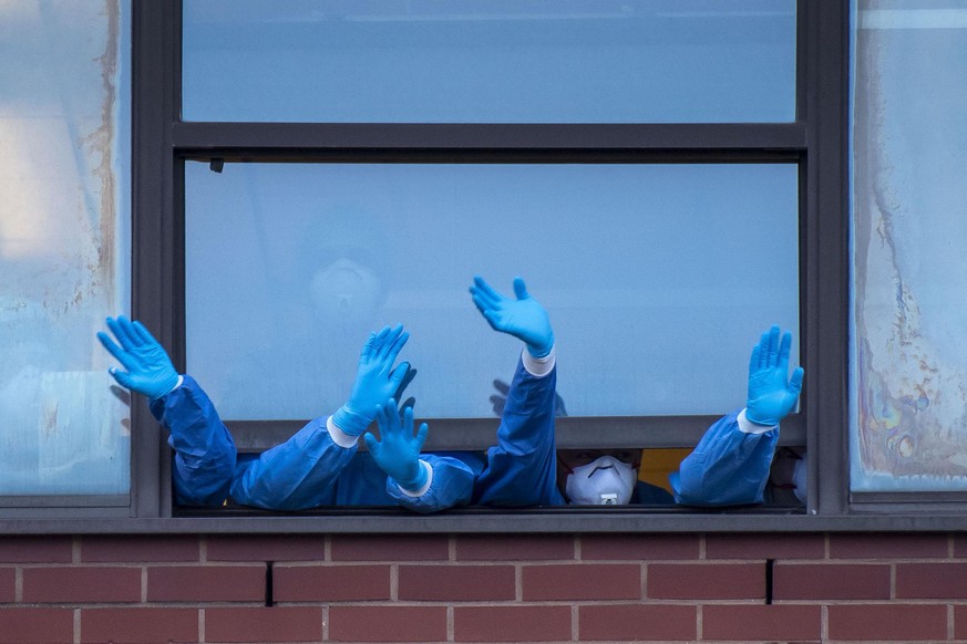 NEWPORT, UNITED KINGDOM - APRIL 23: Health workers wearing PPE clap from a window at the Royal Gwent Hospital on April 23, 2020 in Newport, United Kingdom. Following the success of the &quot;Clap for  ...