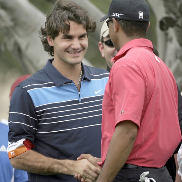 Tiger Woods of the US greets world top-ranked tennis player Roger Federer of Switzerland on the 13th green during the fourth round of the Dubai Desert Classic in Dubai, United Arab Emirates, Sunday, F ...
