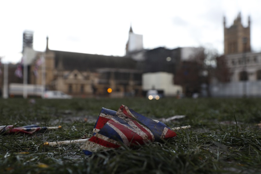 A British Union flag from Brexit day celebrations lies in the grass in front of the Palace of Westminster in London, early Saturday, Feb. 1, 2020. Britain officially left the European Union on Friday  ...