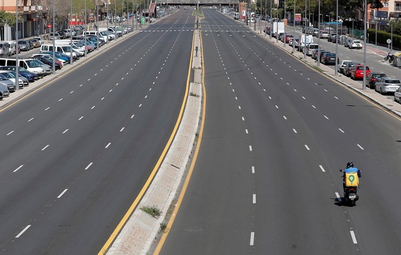 epaselect epa08359122 A deliverer rides on a scooter along an empty highway in Valencia, Spain, 12 April 2020. Spain is currently under lockdown due to the coronavirus pandemic. EPA/KAI FOERSTERLING
