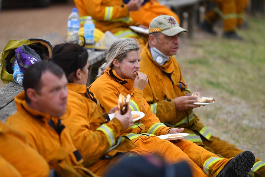 epa08115474 Firefighters rest at Kingscote oval after fighting fires through the night, on Kangaroo Island, southwest of Adelaide, Australia, 10 January 2020. Country Fire Service volunteers along wit ...