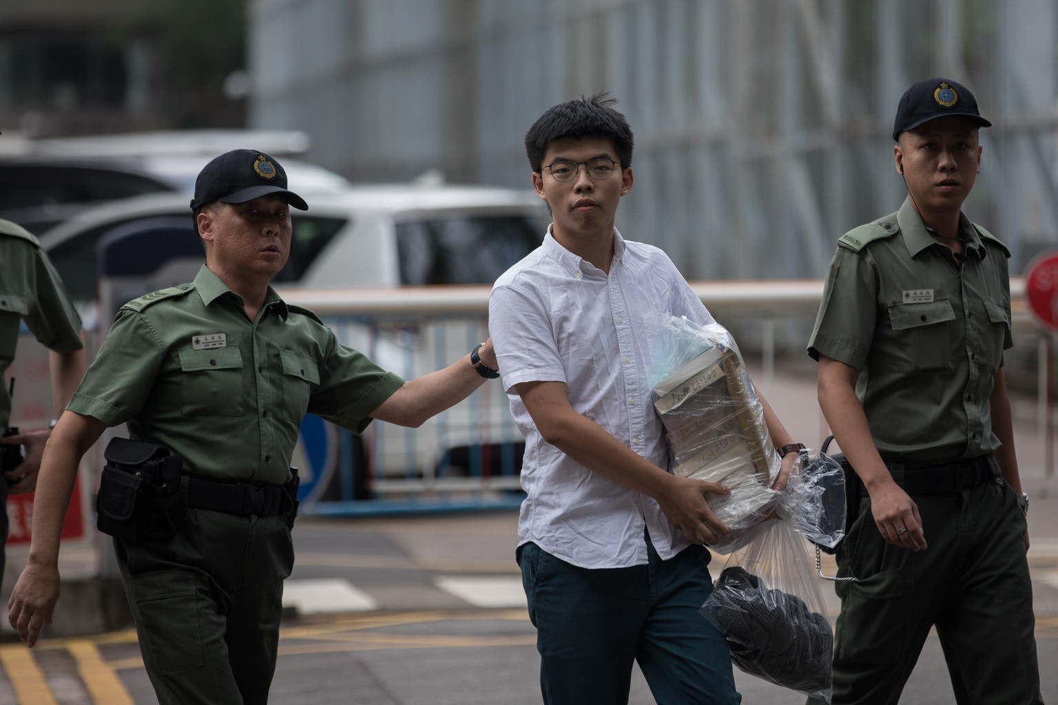 epaselect epa07653193 Demosisto Secretary General and pro-democracy activist Joshua Wong (C) is escorted out of the Lai Chi Kok Correctional Institute Hong Kong, China, 17 June 2019. Wong was sent bac ...