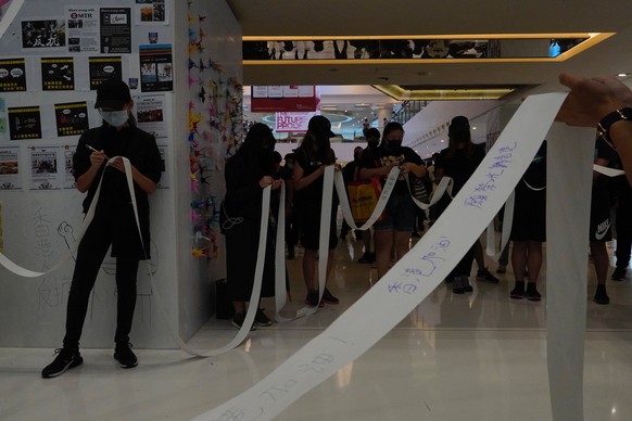Protestors wearing masks grab queuing tickets issued by a pro-Beijing company owned restaurant as they gather at a shopping mall in Hong Kong, Sunday, Oct.13, 2019. Protesters changed tactics and popp ...