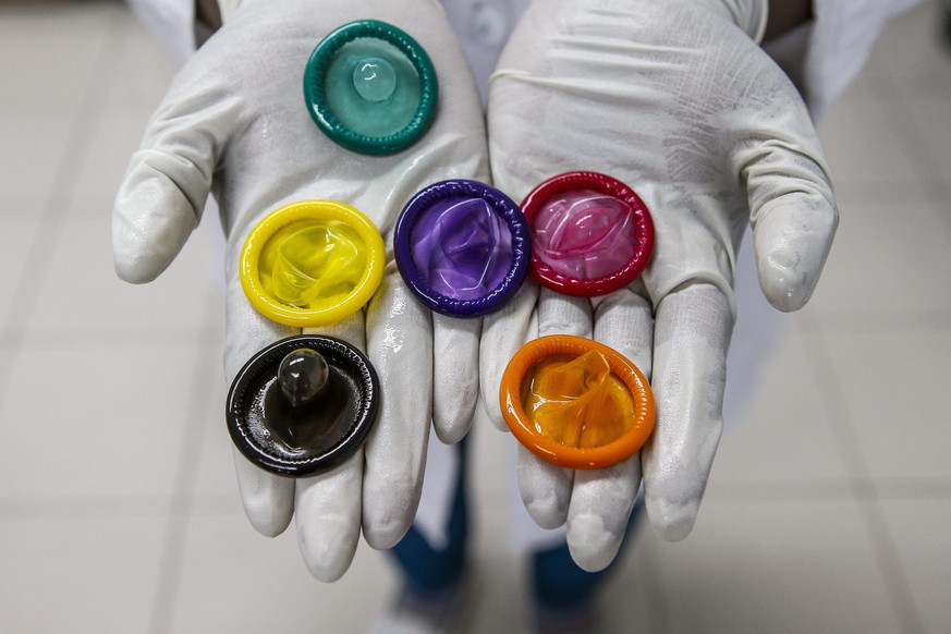 epa04613963 A picture made available on 11 February 2015 shows a worker holding a variety of colored condoms at the Karex condom factory in Port Klang, Malaysia, 17 January 2015. Karex is one of the w ...