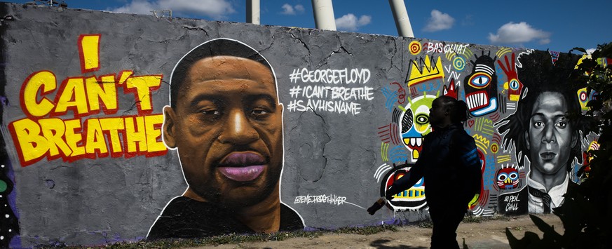 A man walk in front of a graffiti by artist &#039;EME Freethinker&#039; that depict George Floyd is painted on a wall in the public park Mauerpark in Berlin, Germany, Saturday, May 30, 2020. Floyd die ...