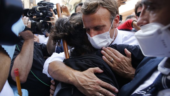 epa08587331 French President Emmanuel Macron hugs a resident as he visits a devastated street of Beirut, Lebanon, 06 August 2020. Macron arrived to Lebanon to show support after a massive explosion on ...