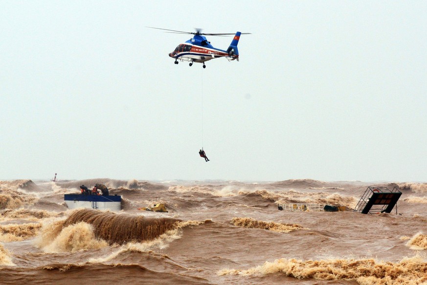 epa08735553 A helicopter from Ministry of Defence rescue stranded crew members at the sea, in Quang Tri province, Vietnam, 11 October 2020. Heavy rains and floods killed nine people and left 11 missin ...