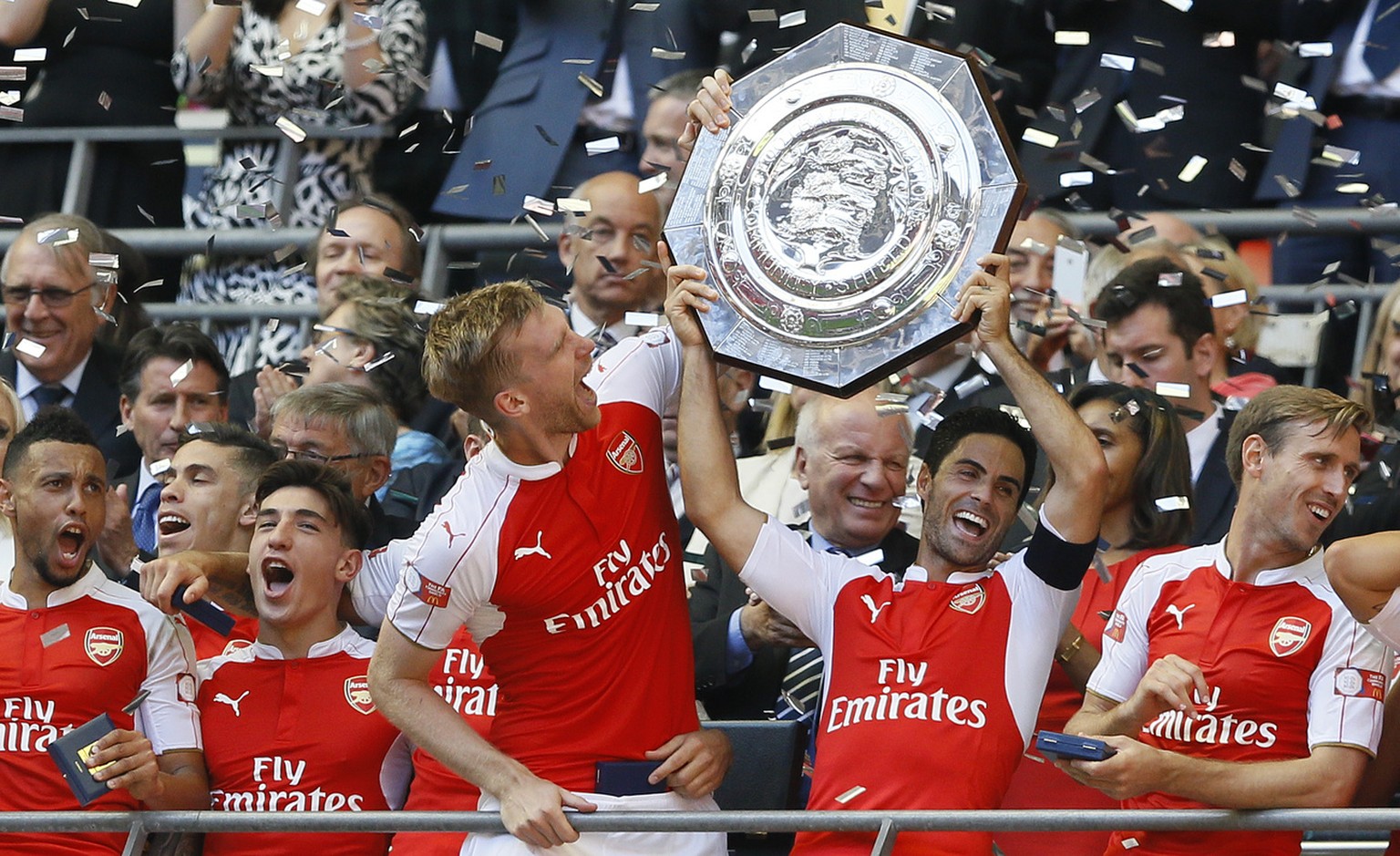 Arsenal&#039;s captain Per Mertesacker, centre, holds the trophy with Mikel Arteta, second right, after winning the English Community Shield soccer match between Arsenal and Chelsea at Wembley Stadium ...