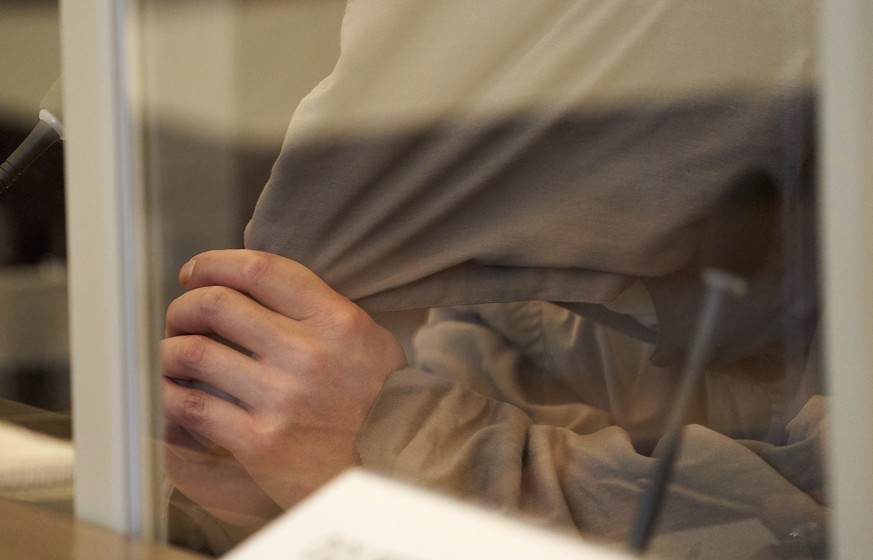 One of the defendants, Eyad A. (43), is sitting on the bench of the Higher Regional Court behind Corona protective screens, hiding his face under a hood in Koblenz, Germany, Thursday, April 23, 2020.  ...