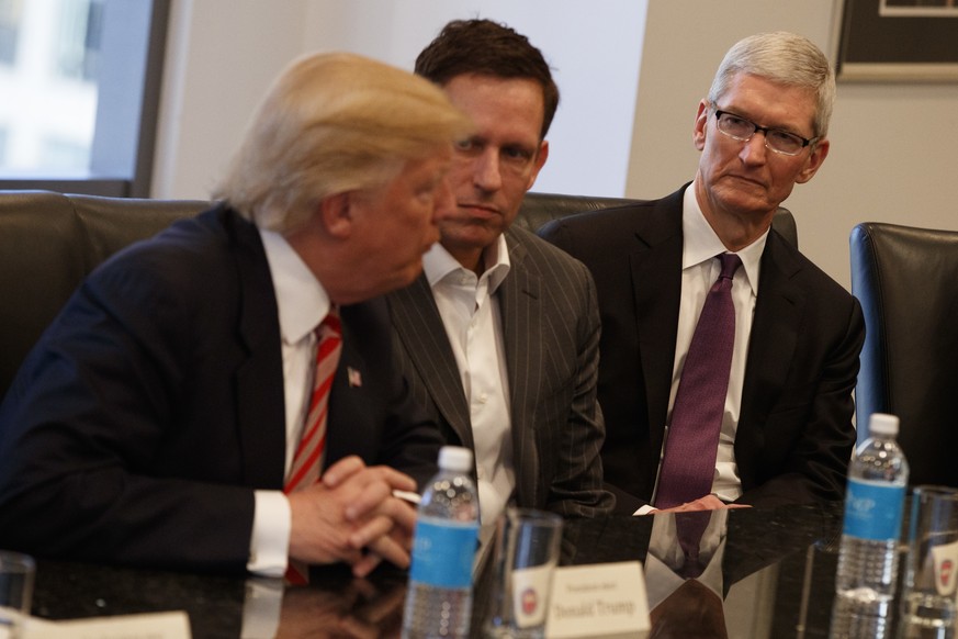 Apple CEO Tim Cook, right, and PayPal founder Peter Thiel, center, listen as President-elect Donald Trump speaks during a meeting with technology industry leaders at Trump Tower in New York, Wednesday ...