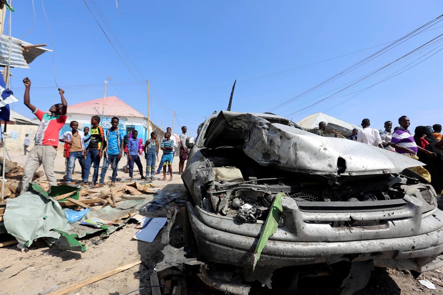 Civilians stand near a car destroyed in a suicide bomb explosion at the Wadajir market in Madina district of Somalia&#039;s capital Mogadishu, February 19, 2017. REUTERS/Feisal Omar