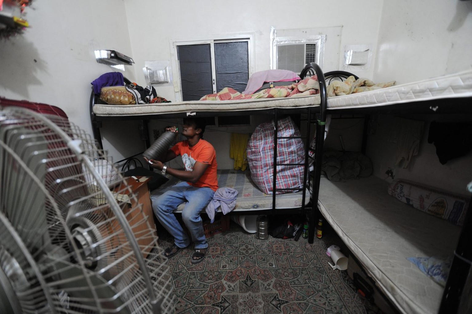 epa03955192 An Amnesty International handout photo dated 2012 shows a migrant worker sitting on a bunk bed in his accommodation in Qatar. Amnesty International on 17 November 2013 released a report bl ...