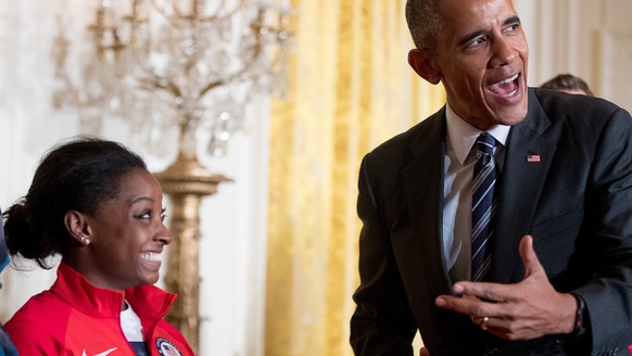 President Barack Obama leans over to speak to US Olympics gymnast Simone Biles in the East Room the White House in Washington, Thursday, Sept. 29, 2016, during a ceremony where he honored members of t ...