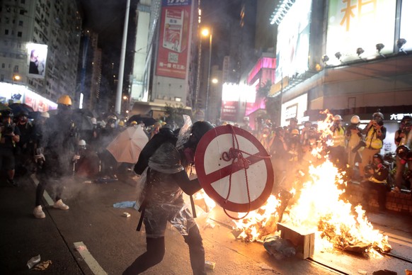 FILE - In this Aug. 31, 2019, file photo, a protester uses a shield to cover himself as he faces police in Hong Kong. Protesters and police are standing off in Hong Kong on a street that runs through  ...