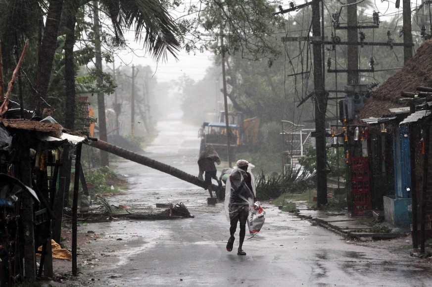 epa08433356 A man walks in heavy rain and wind as cyclone Amphan approaches the Odisha coast, Paradeep, India, 20 May 2020. Cyclone Amphan, termed as &#039;super cyclone&#039; approaches through the B ...